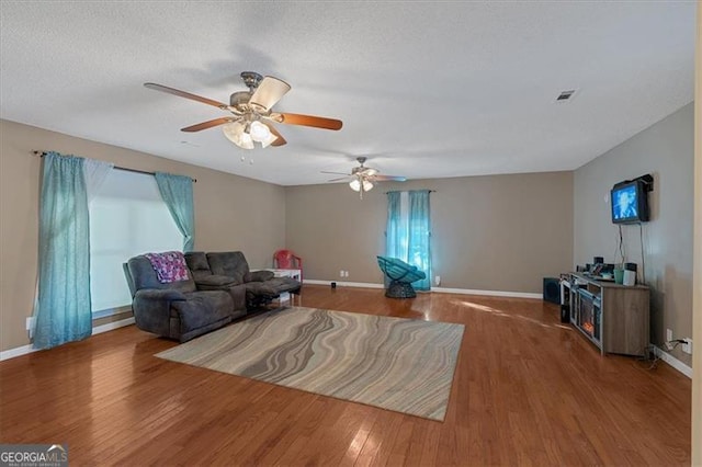 living room with a textured ceiling, hardwood / wood-style flooring, and ceiling fan