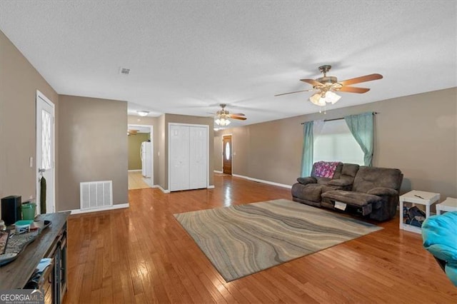 living room with light wood-type flooring and a textured ceiling