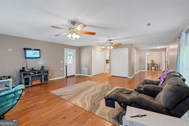 living room with wood-type flooring, a textured ceiling, and ceiling fan