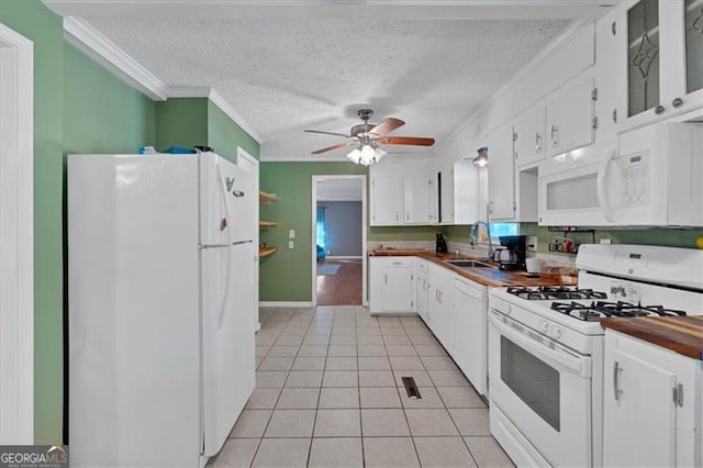 kitchen with sink, light tile patterned floors, crown molding, white appliances, and white cabinets