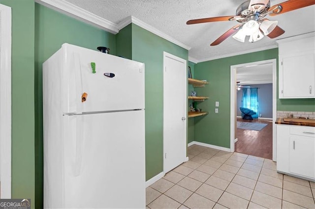 kitchen featuring white cabinets, light tile patterned floors, white fridge, and ornamental molding