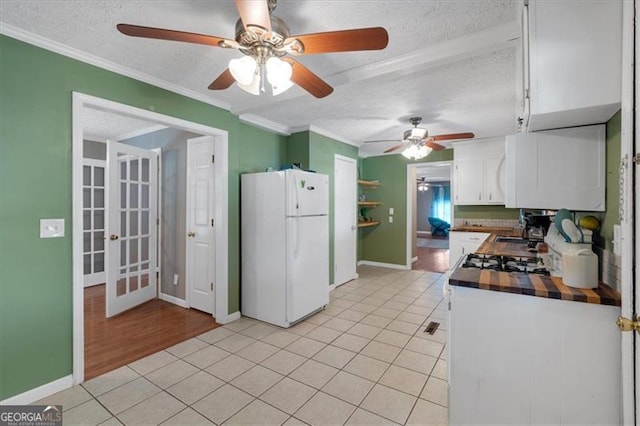 kitchen with white cabinets, a textured ceiling, white refrigerator, and crown molding