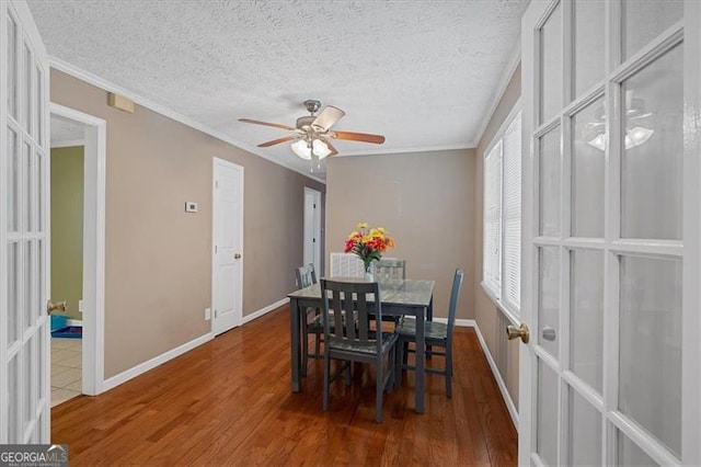 dining space with french doors, a textured ceiling, ceiling fan, crown molding, and wood-type flooring