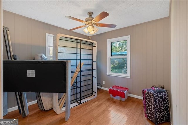 office space with ceiling fan, wood walls, and wood-type flooring