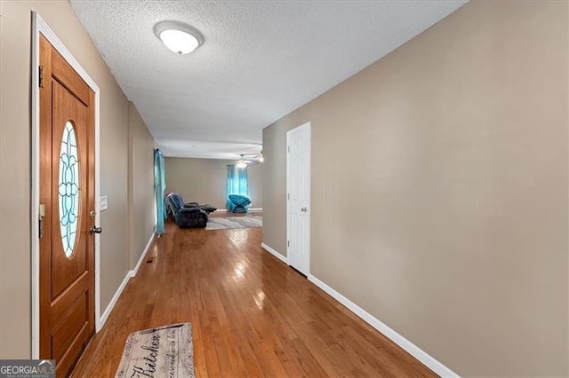 hall featuring light hardwood / wood-style floors and a textured ceiling