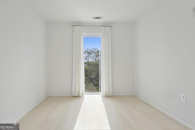 empty room with light hardwood / wood-style flooring and a healthy amount of sunlight