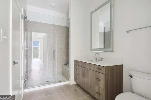 bathroom featuring vanity, a shower with shower door, tile patterned floors, and toilet