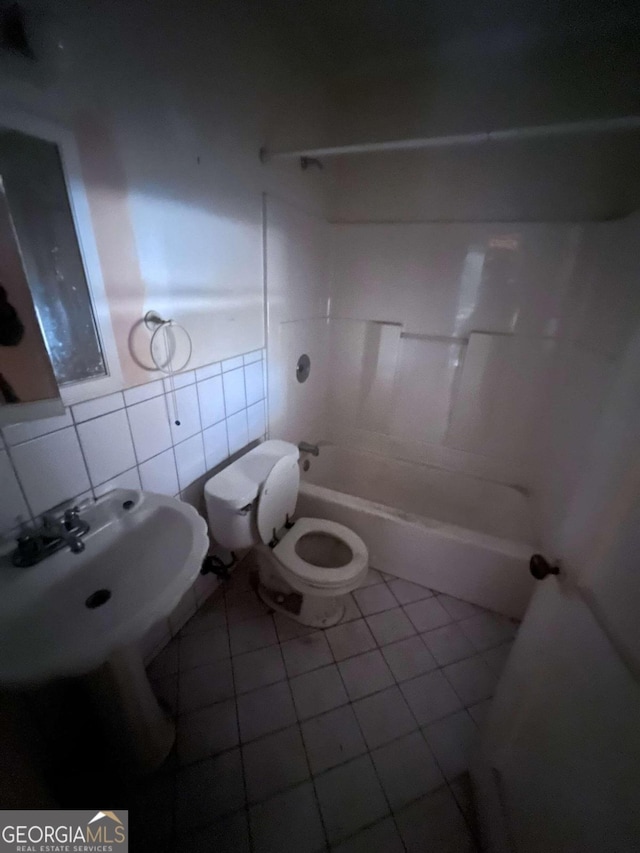 bathroom featuring toilet, shower / washtub combination, tile patterned floors, and tile walls