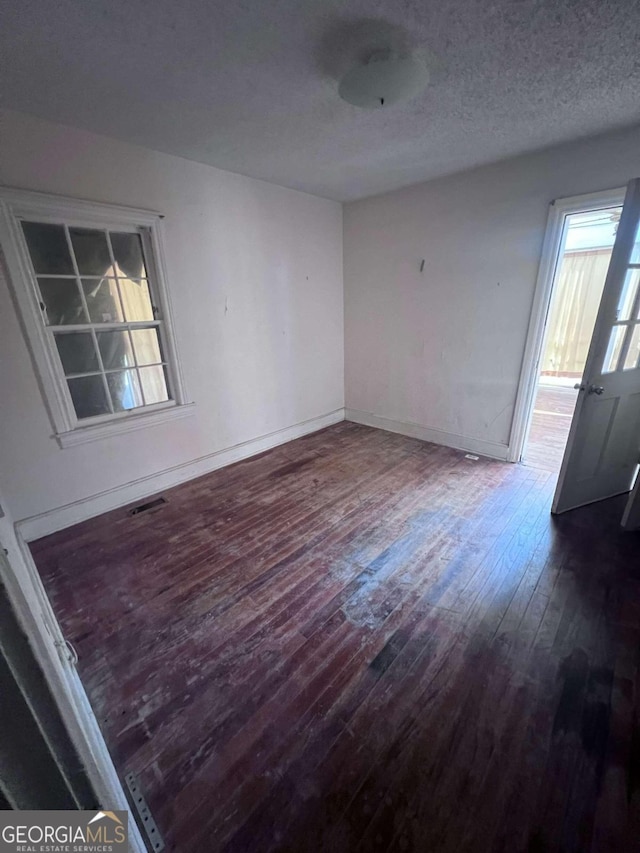 spare room with a textured ceiling and dark hardwood / wood-style floors