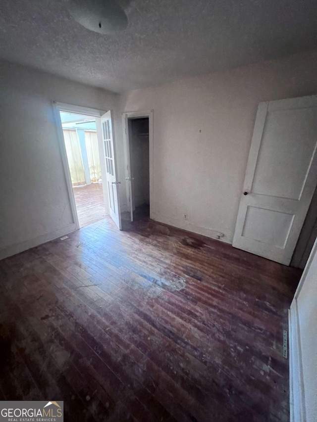 unfurnished bedroom with a textured ceiling and dark hardwood / wood-style floors