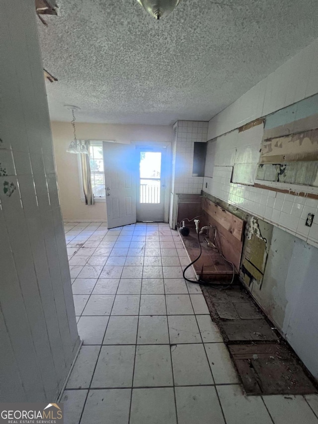 interior space featuring white cabinets, light tile patterned floors, and a textured ceiling