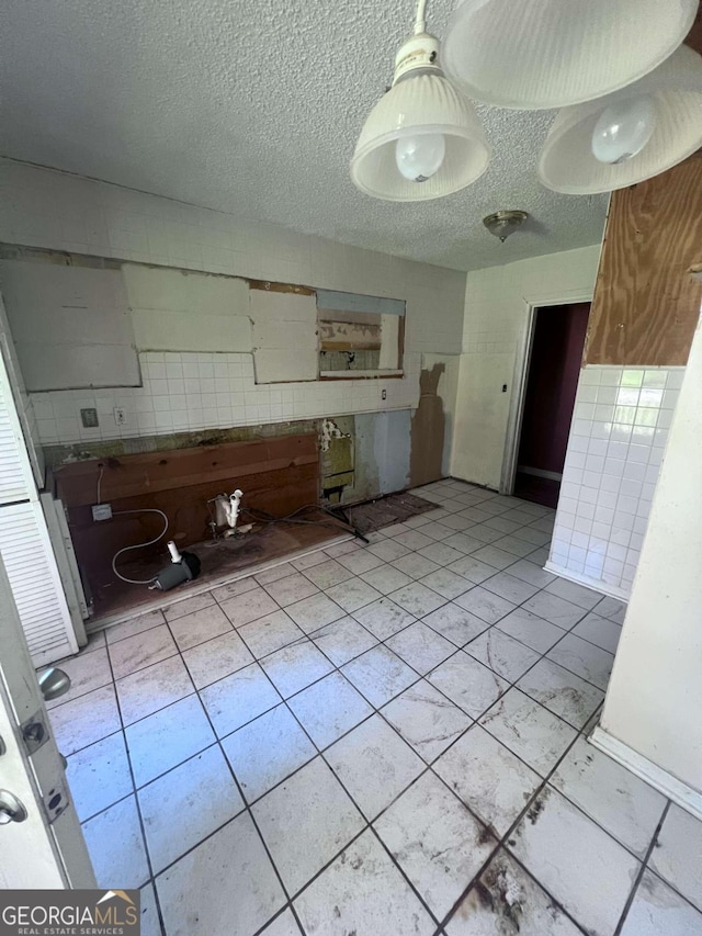 kitchen featuring tile walls, light tile patterned floors, and a textured ceiling