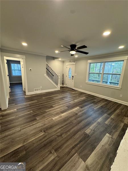 unfurnished living room featuring ceiling fan, dark hardwood / wood-style flooring, and crown molding