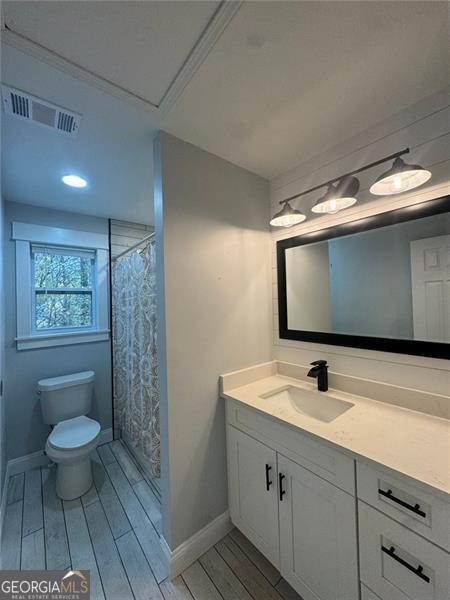 bathroom with hardwood / wood-style floors, vanity, toilet, and walk in shower