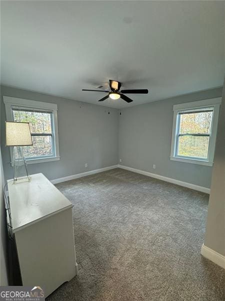 carpeted spare room featuring ceiling fan and a healthy amount of sunlight