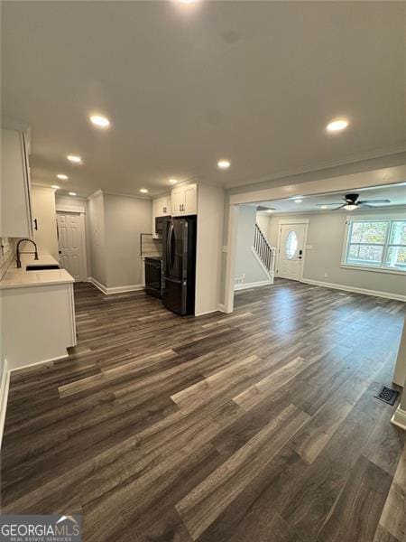 unfurnished living room featuring dark hardwood / wood-style floors, ceiling fan, and sink