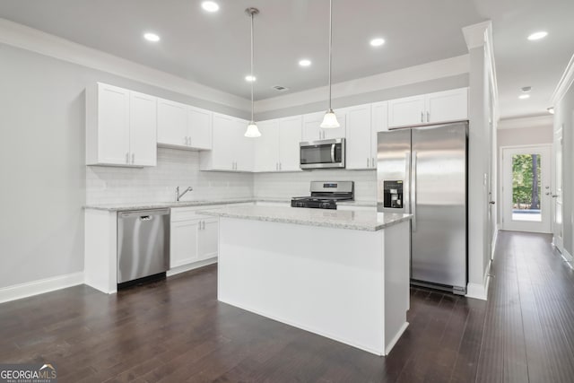 kitchen with appliances with stainless steel finishes, decorative light fixtures, white cabinetry, a center island, and light stone counters