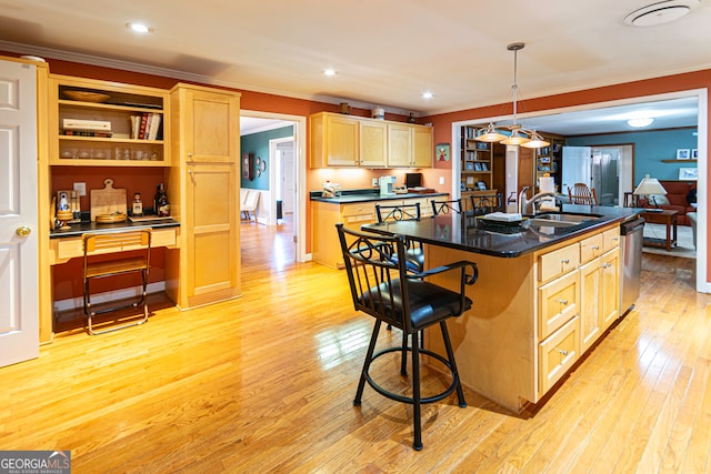 kitchen with sink, dishwasher, light hardwood / wood-style floors, hanging light fixtures, and an island with sink