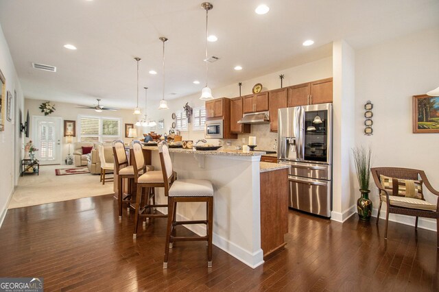 kitchen with ceiling fan, light stone countertops, decorative light fixtures, a kitchen bar, and stainless steel appliances