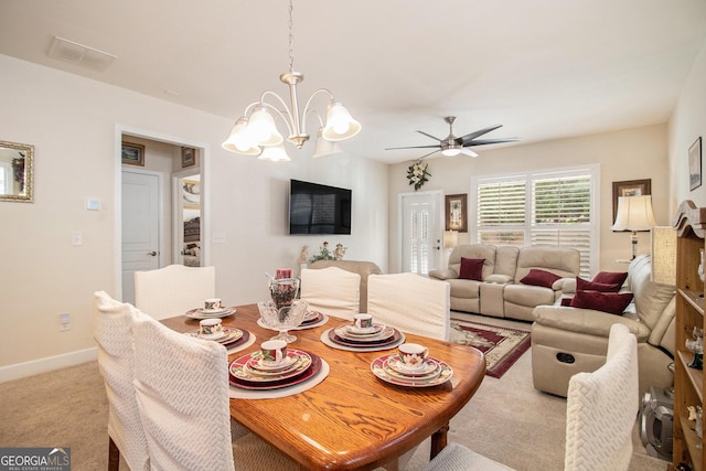 dining room with light carpet and ceiling fan with notable chandelier