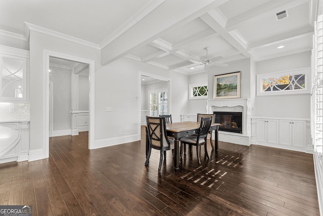 dining space with coffered ceiling, ceiling fan, crown molding, dark wood-type flooring, and beam ceiling