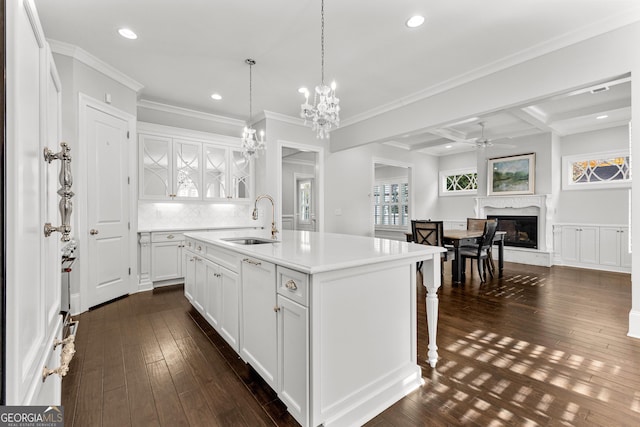 kitchen with a high end fireplace, dark wood-type flooring, sink, white cabinetry, and an island with sink