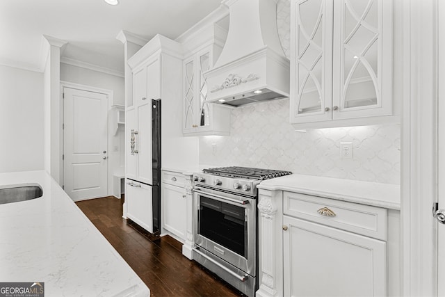 kitchen with custom exhaust hood, white cabinetry, and high end range