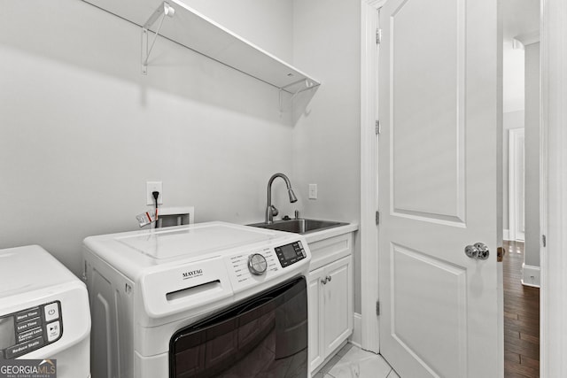 laundry area with cabinets, light hardwood / wood-style floors, separate washer and dryer, and sink