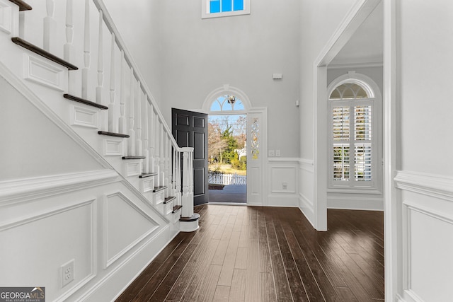 foyer featuring dark hardwood / wood-style flooring, crown molding, and a high ceiling