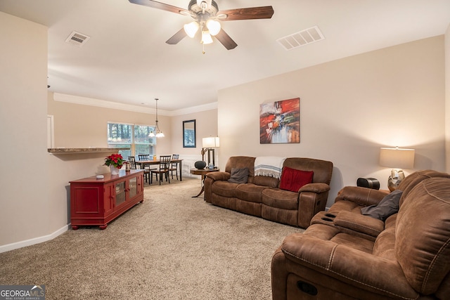 carpeted living room with ceiling fan and ornamental molding