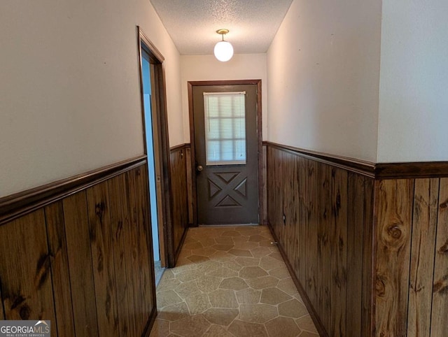 doorway to outside featuring wood walls and a textured ceiling