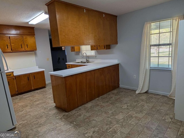 kitchen with white refrigerator, sink, a textured ceiling, light hardwood / wood-style floors, and kitchen peninsula