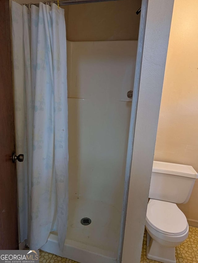 bathroom with a shower with curtain and toilet