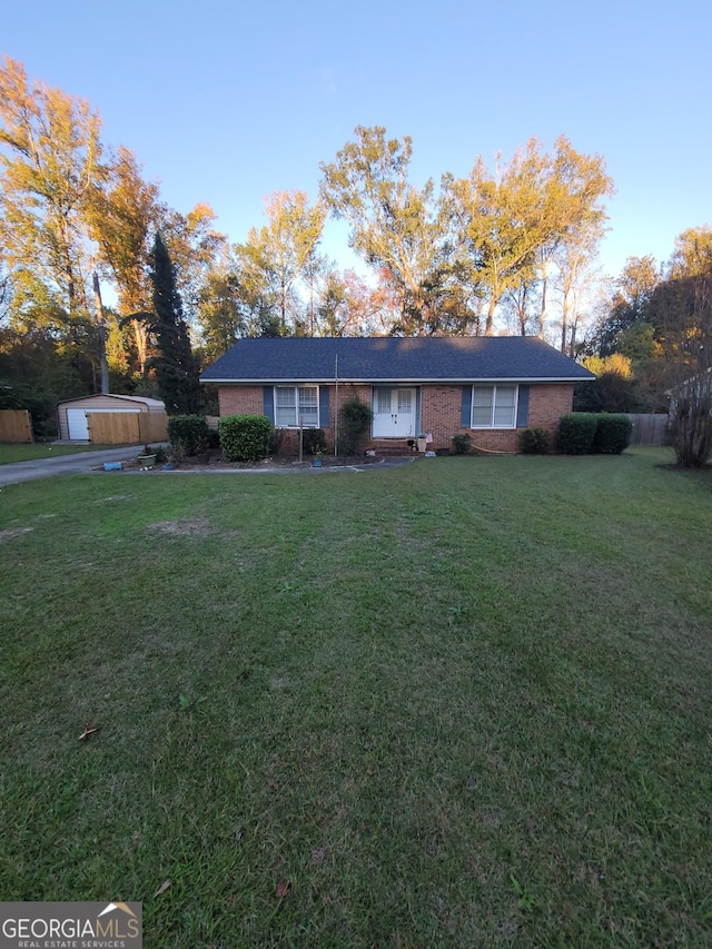 ranch-style house with a garage, an outdoor structure, and a front lawn