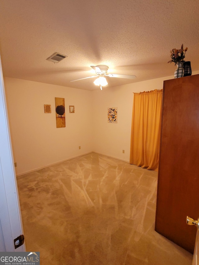 spare room featuring ceiling fan, carpet, and a textured ceiling