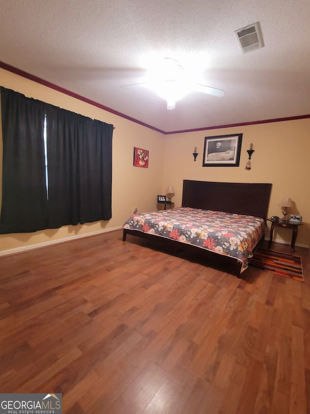 bedroom with ceiling fan, wood-type flooring, a textured ceiling, and ornamental molding