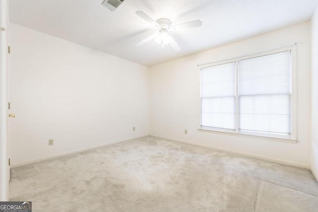 carpeted empty room featuring ceiling fan, a textured ceiling, visible vents, and baseboards