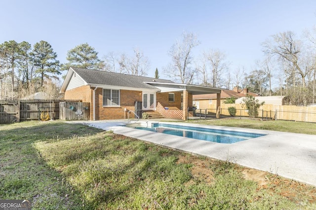 rear view of house with french doors, brick siding, a lawn, and a fenced backyard