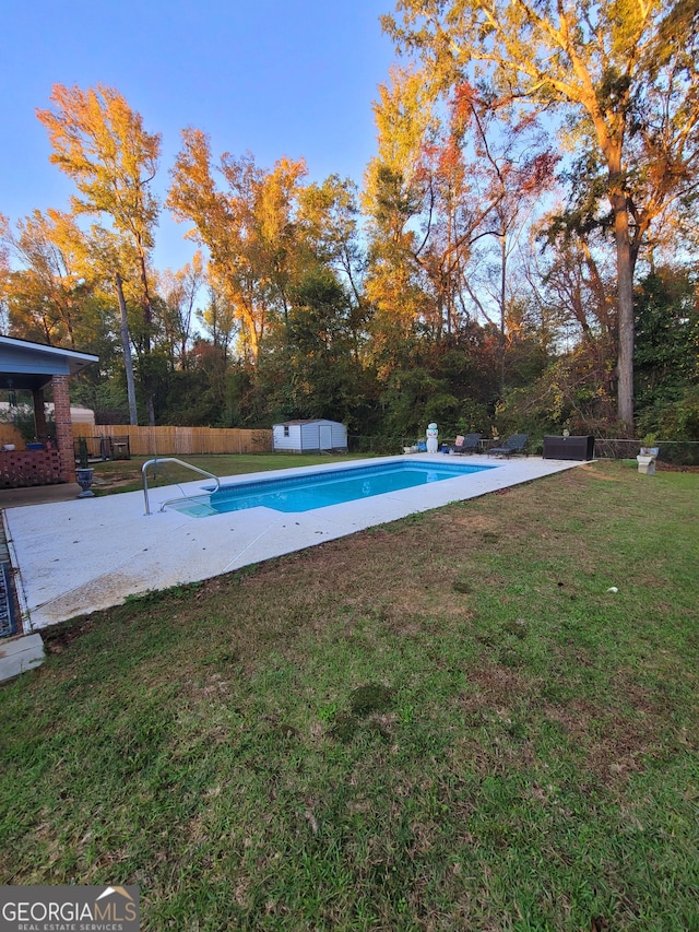 view of swimming pool featuring a yard and a storage shed