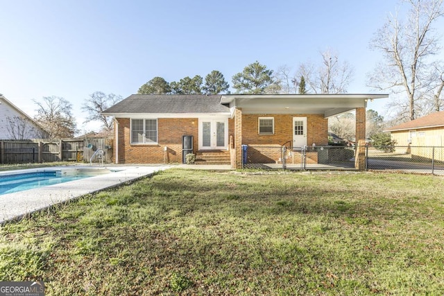 rear view of house featuring a yard, a fenced backyard, a fenced in pool, and french doors