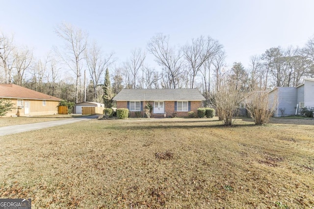 ranch-style home featuring an outbuilding, brick siding, and a front lawn