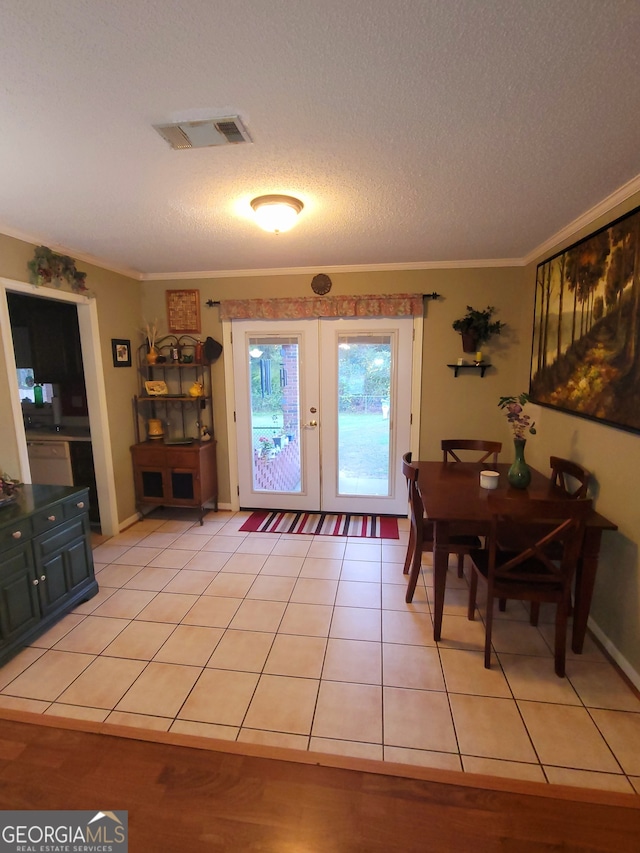 doorway to outside with french doors, light tile patterned floors, a textured ceiling, and ornamental molding