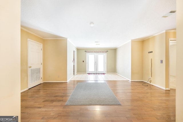 unfurnished room with visible vents, ornamental molding, light wood-style flooring, and baseboards