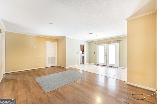 entryway with a textured ceiling, french doors, wood finished floors, and crown molding