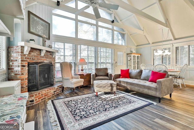 sunroom / solarium featuring ceiling fan with notable chandelier, vaulted ceiling with beams, and a brick fireplace