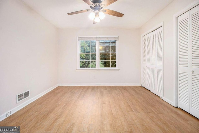 unfurnished bedroom featuring two closets, ceiling fan, and light hardwood / wood-style floors