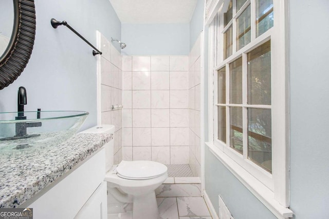 bathroom featuring tiled shower, vanity, and toilet