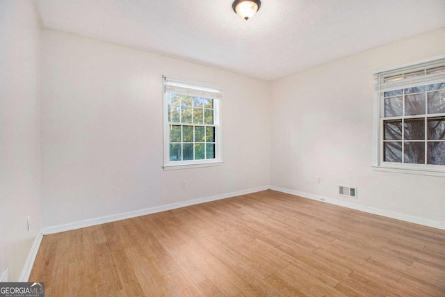 empty room with light hardwood / wood-style flooring and a textured ceiling