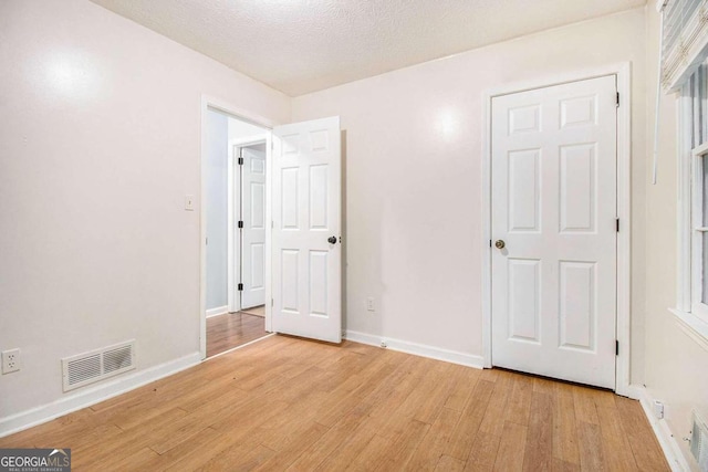 unfurnished bedroom featuring a textured ceiling and light wood-type flooring