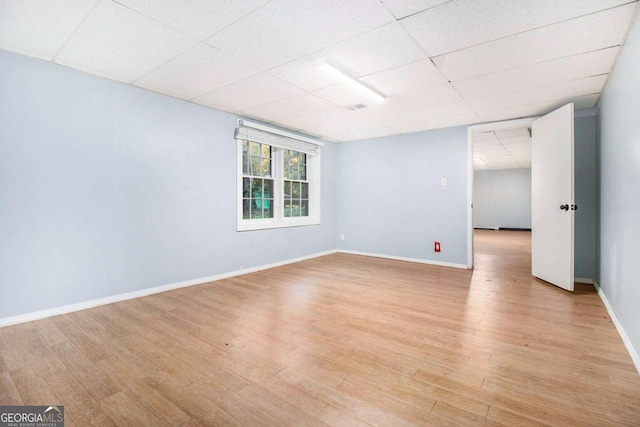 spare room with a paneled ceiling and light hardwood / wood-style floors